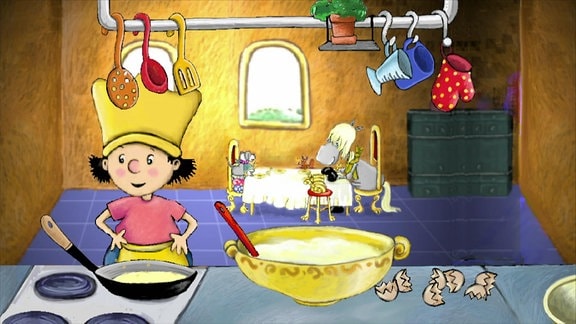 Der kleine König steht in der Küche und bereitet Pfannkuchen zu.
