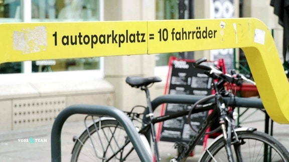 Auf einem Fahrradständer steht die Aufschrift "ein autoparkplatz = 10 Fahrräder".