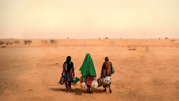 Drei Frauen gehen durch die Wüste.