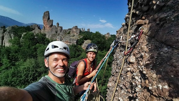 Ein Mann und eine Frau klettern in einem Gebirge an einem Felsen.