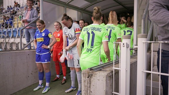 Zwei Frauenfußballmanschaften stehen bereit zum Einlaufen in ein Stadion.