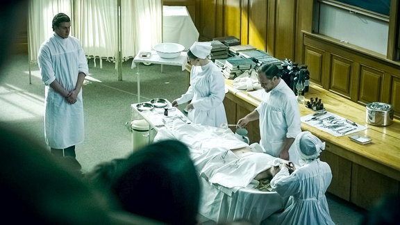 Arzt während einer Operation in einer Vorlesung im Hörsaal mit drei Assistenten