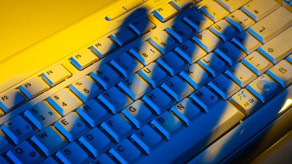 Computer -Tastatur und der Schatten einer Hand