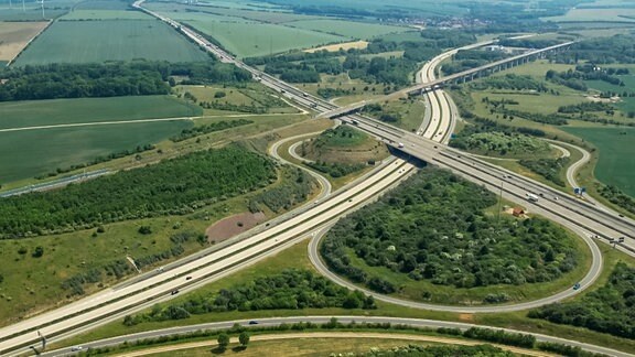 Blick auf ein Autobahnkreuz in einer grünen Landschaft.