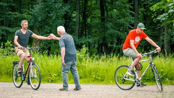 Mann begrüßt zwei fahrende Fahradfahrer