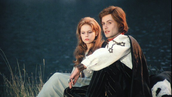 Ein junger Prinz und eine junge Frau sitzen an einem Ufer.