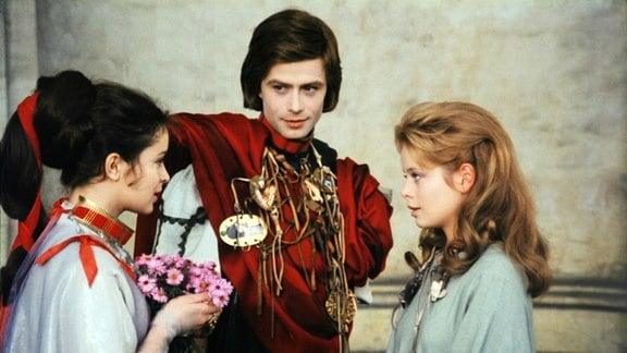 Ein junger Prinz steht mit zwei jungen Frauen beisammen.
