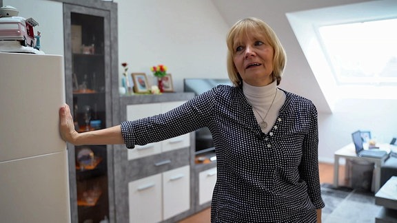 Eine Frau steht abgestützt an einem Schrank in einem Kinderzimmer. 