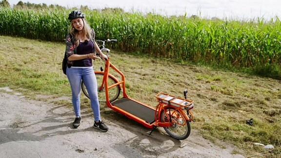 Eine Frau steht neben einem großen Roller.