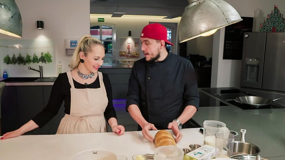 Eine Frau und ein Mann stehen in einer Küche und sprechen über Brot