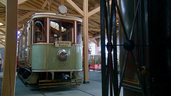 Ein alter Straßenbahnwagen steht in einer Halle.