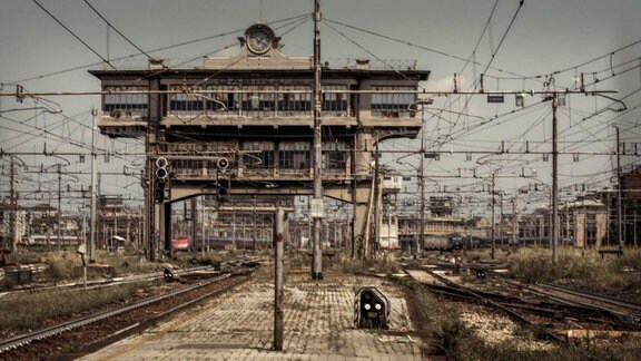 Blick auf ein Bahnhofsgelände mit Schienen, Oberleitungen und alten Gebäuden.
