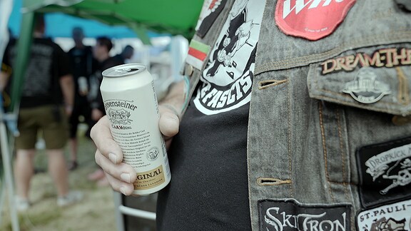 Ein Mann mit einer Büchse Bier, die er vor seinem Bauch hält.