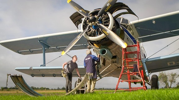 Zwei Männer arbeiten an einem historischen Doppeldecker-Flugzeug