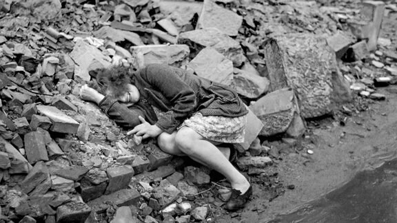 historisches Foto: liegende, weinende Frau auf einem Trümmerberg