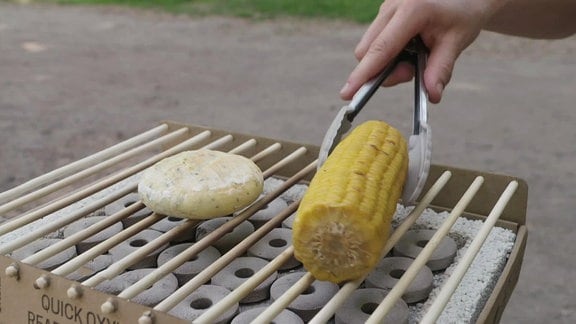 Ein Maiskolben und ein Käse auf einem Grill.