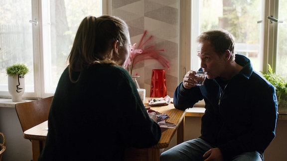 Eine Frau und ein Mann sitzen an einem Tisch und trinken Kaffee.