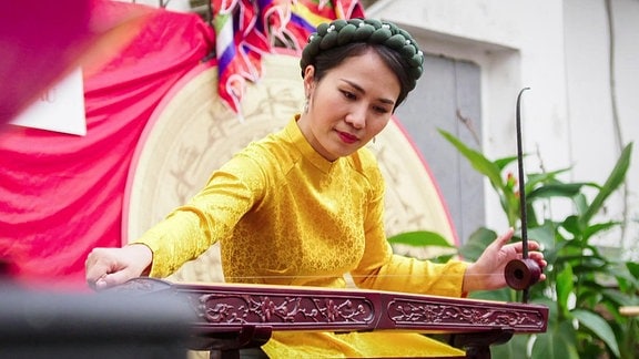 junge Asiatin spielt auf einem typisch asiatischen Instrument
