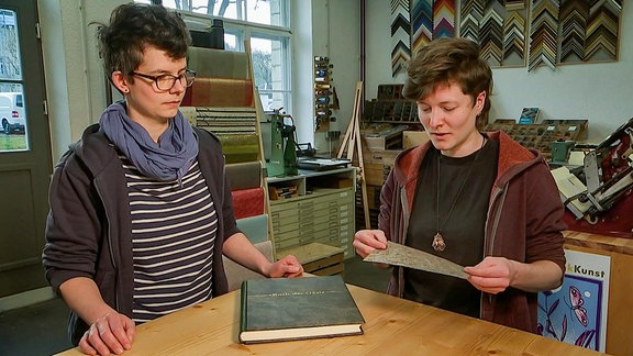 zwei Buchbinderinnen stellen ein "Buch der Gäste" vor