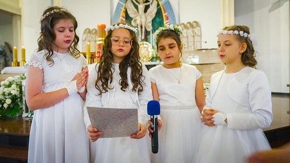 vier Mädchen singen in einer Kirche
