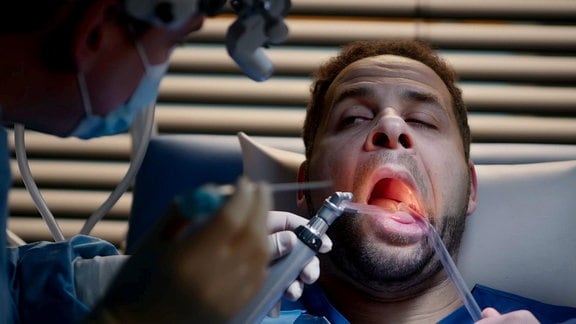 Ein Mann bei einer Untersuchung in seinem geöffneten Mund.