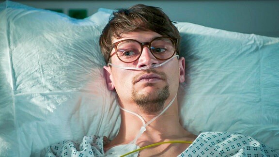 junger Mann mit Brille im Krankenbett
