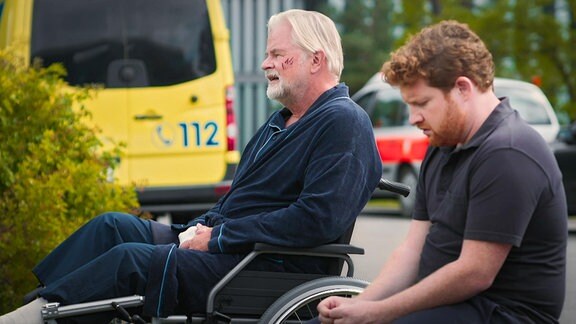 Mann im Rollstuhl unterhält sich mit jüngeren Mann