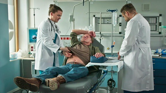 Ärztin und Arzt versorgen einen liegenden Patienten