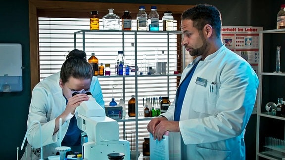 zwei Ärzte in einem Labor, ein Arzt schaut durch ein Mikroskop