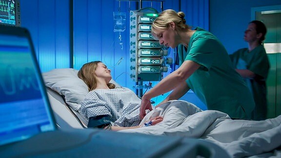 zwei Krankenschwestern pflegen eine liegende Patientin