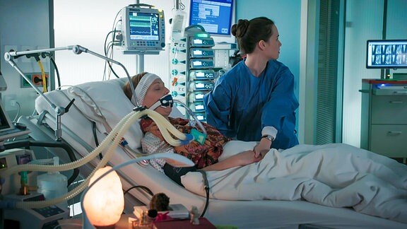Schwester behandelt eine Patientin am Beatmungsgerät