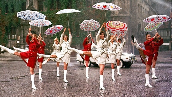 Frauen tanzen im Regen mit Regenschirmen