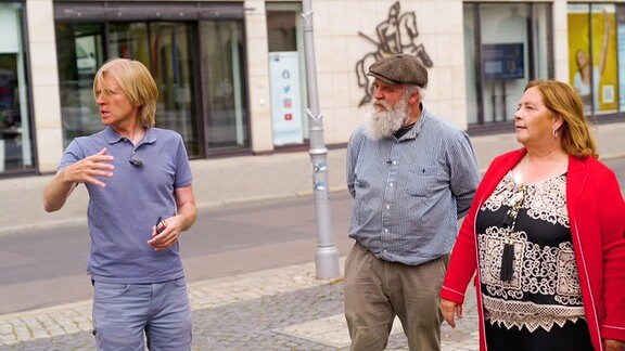 Zwei Männer und eine Frau stehen auf einer Straße.