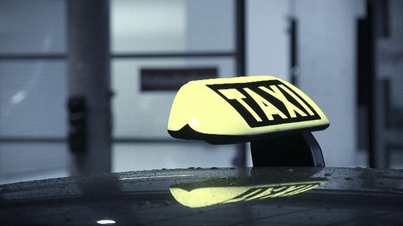 Ein Taxischild auf einem Autodach.