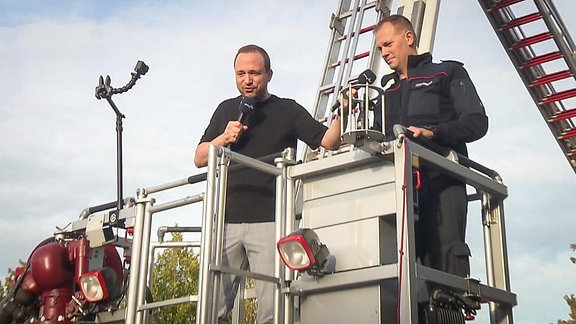 Moderator und Feuerwehrmann auf einer Feuerwehr-Hebebühne