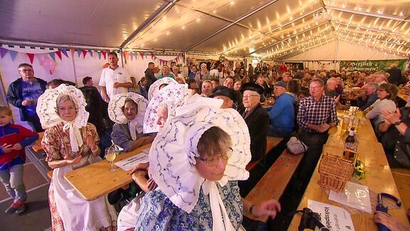 Blick in ein Festzelt mit vielen Menschen. Einige davon in einer Tracht.