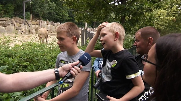 Ein Junge in einem Zoo spricht in ein Mikrofon.