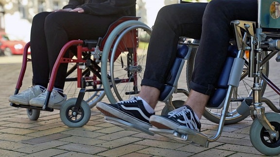 Ansicht der Beine zweier Menschen in Rollstühlen.
