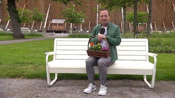 Mario D. Richardt auf einer Bank mit einem Blumenstrauß