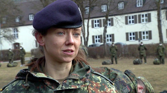 Eine Majorin der Bundeswehr steht vor einer Kaserne.