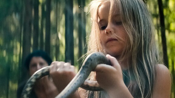 Mädchen im Wald mit Schlange in der Hand