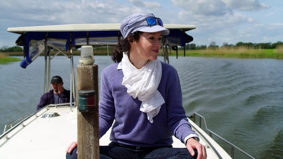 Eine Frau sitzt auf einem Boot und schaut aufs Wasser.
