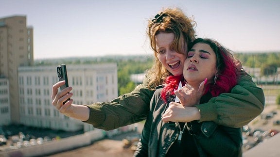 zwei Frauen machen ein "Selfie" auf dem Dach einer Hauses