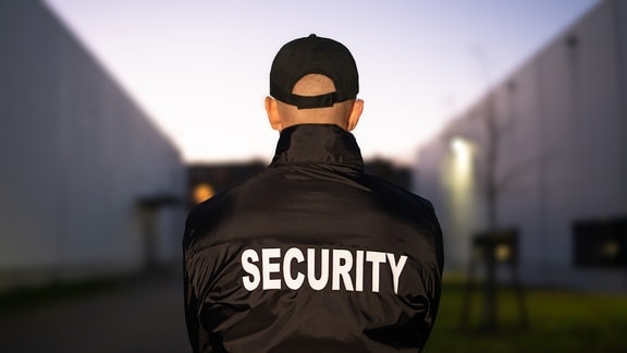Mann mit schwarzer Jacke mit Aufschrift "Security"