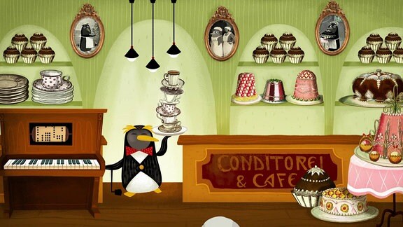 Ein Pinguin in Kellnerkleidung balanciert einen Stapel Tassen im Café einer Conditorei.  