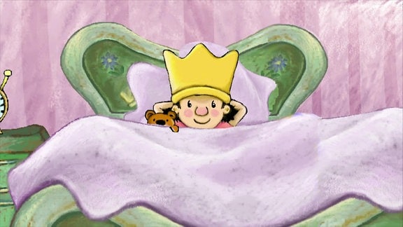 Der kleine König liegt mit seinem Teddy zugedeckt in seinem Bett.
