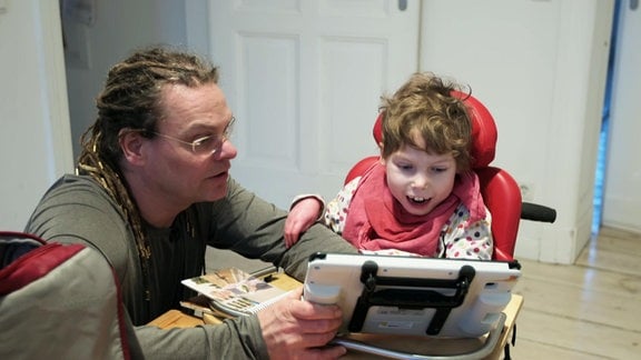 Ein Mann mit einem Kind an einem Tabletcomputer.
