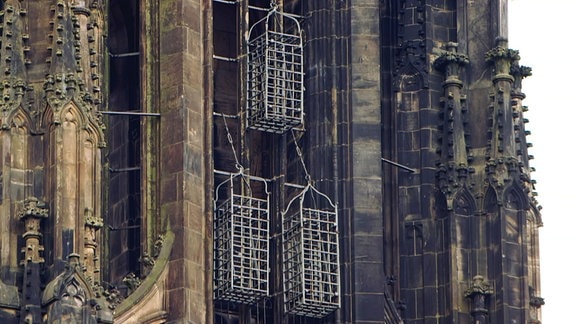 Drei eiserne Käfige hängen an der Außenseite der Sankt Lamberti Kirche  zu Münster.