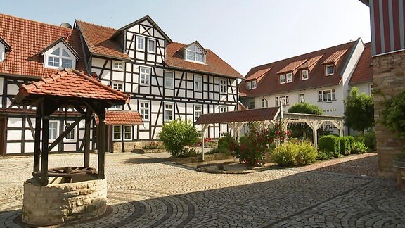 Blick auf eine Fachwerkhaus an einem Innenhof mit Ziehbrunnen.