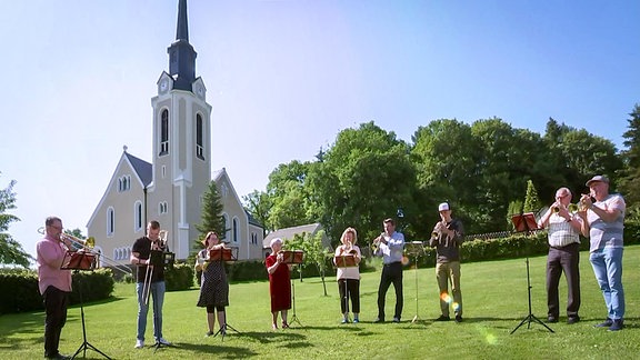 Bläsergruppe auf einer Wiese vor einer Kirche